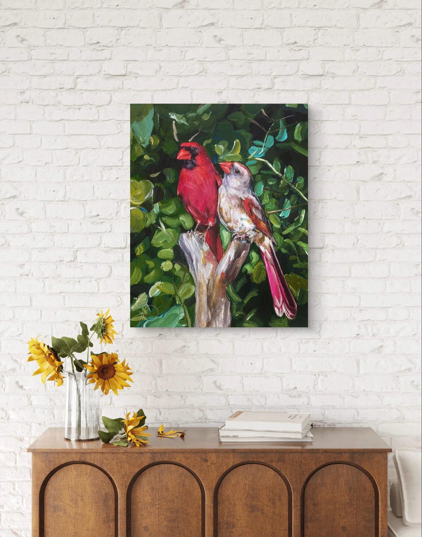 Acrylgemälde Kardinäle (Paar) hängt an weißer Backsteinwand über Holzkommode mit Sonnenblumen
